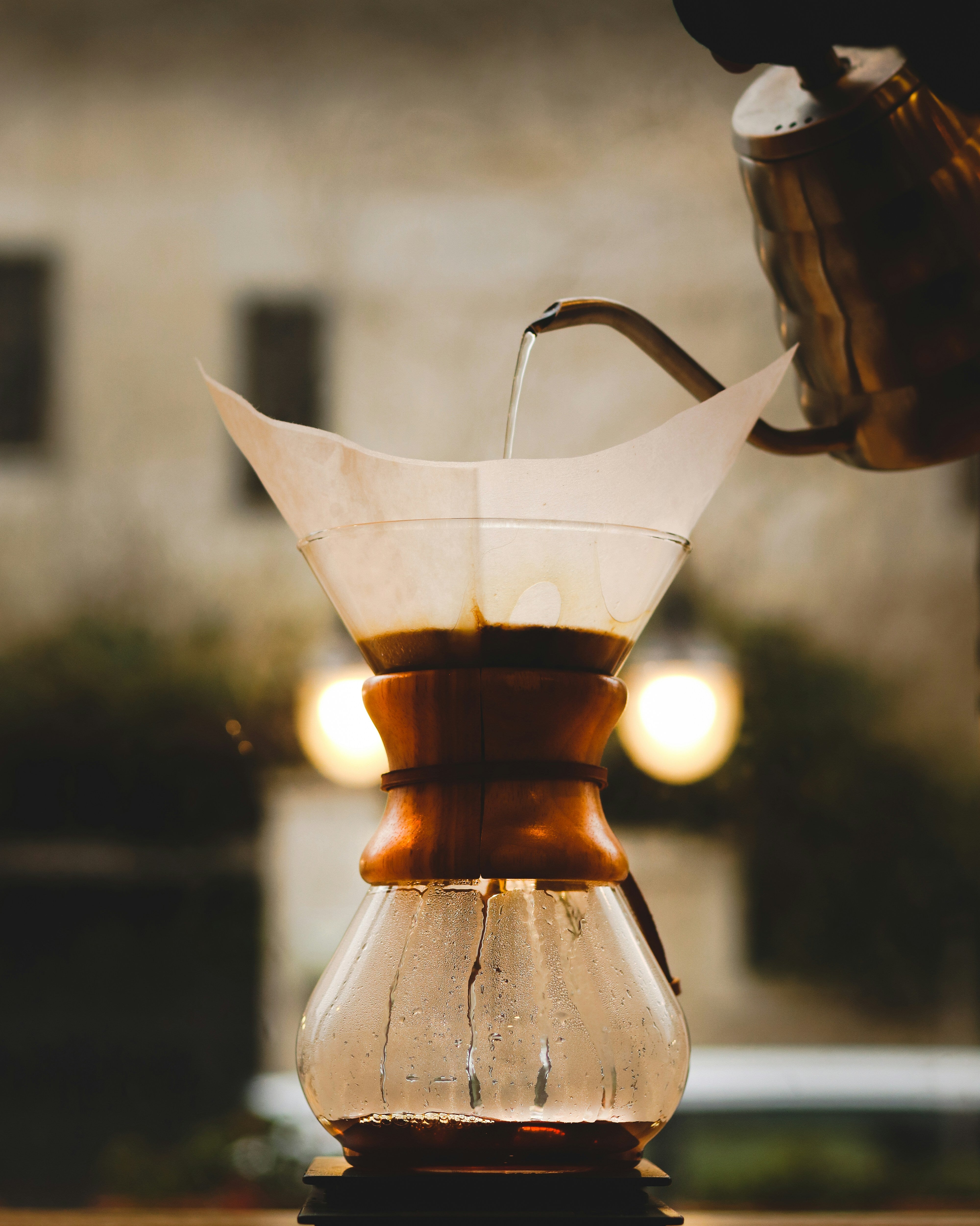 Coffee being poured into a glass coffee maker with a blurred background